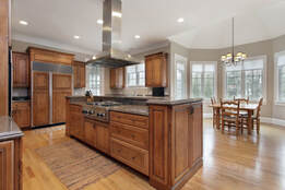 Oak kitchen with wood floors and modern appliances in a room with many windows