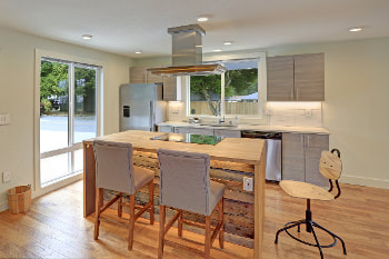 Modern kitchen Picture with Maple floors and counter tops. Gray cabinets, appliances and stools. Island is underlighted to show rustic wood paneling on the island face.