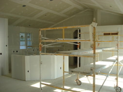 Picture of the interior of a newly built home that has been drywalled and is ready to paint. 