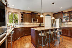 Mahogony cabinet kitchen with recessed lighting and tan marble countertops and oak wood floors. Contempory style kitchen.